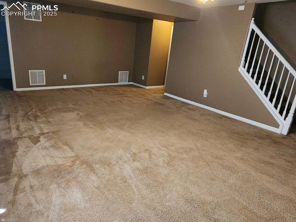 Image 12 of 17: Finished below grade area featuring stairway and light colored carpet