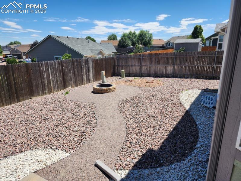 Image 17 of 17: Fenced backyard with an outdoor fire pit and a residential view
