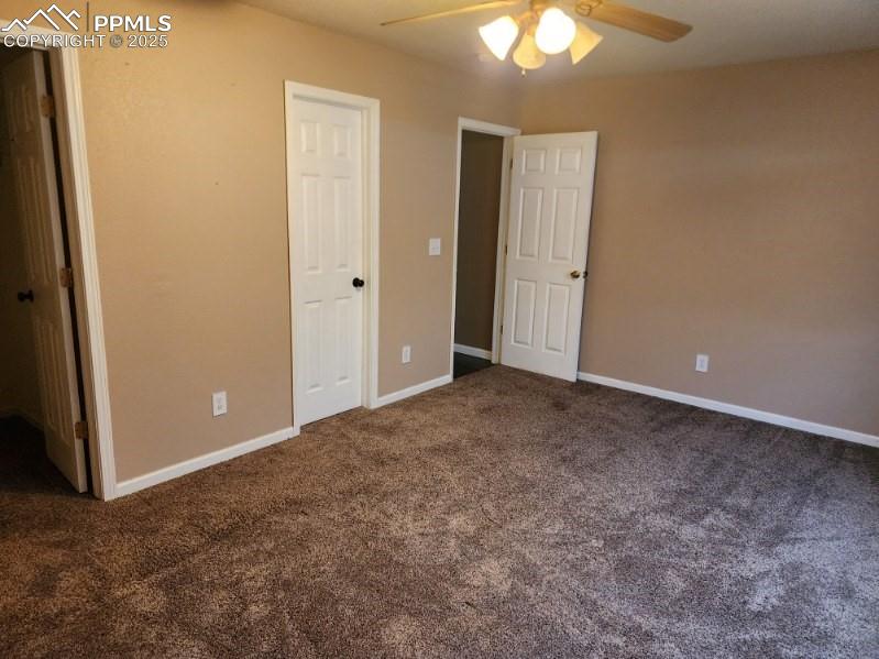 Image 2 of 17: Unfurnished bedroom with dark carpet and ceiling fan