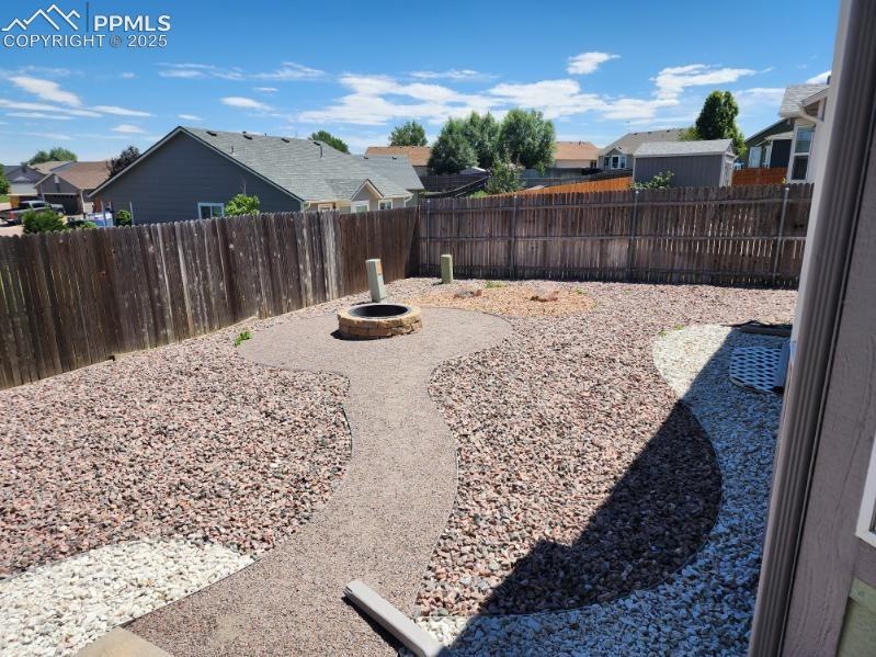 Image 20 of 20: Fenced backyard with an outdoor fire pit and a residential view