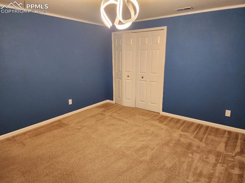 Image 5 of 17: Unfurnished bedroom with carpet, crown molding, and a closet