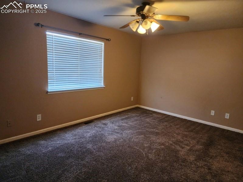 Image 7 of 17: Empty room with dark colored carpet and a ceiling fan