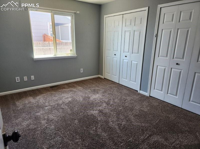 Image 8 of 17: Unfurnished bedroom with two closets and dark carpet