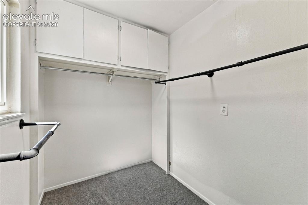 Image 14 of 30: Built-in white cabinetry, metal hanging rods, and carpeted flooring