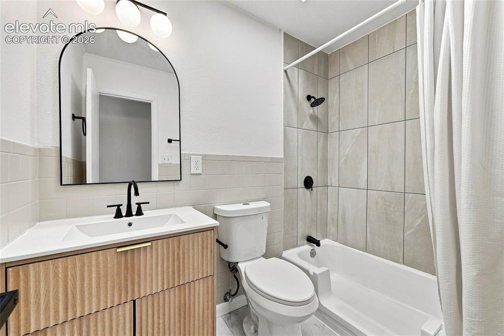 Image 15 of 30: Bathroom featuring a wood-finish vanity with a white countertop, matte blac