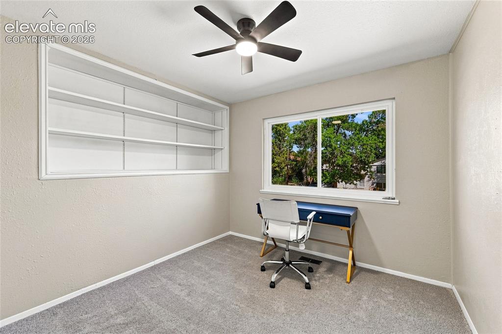 Image 16 of 30: Built-in shelving, ceiling fan with integrated lighting, window with exteri