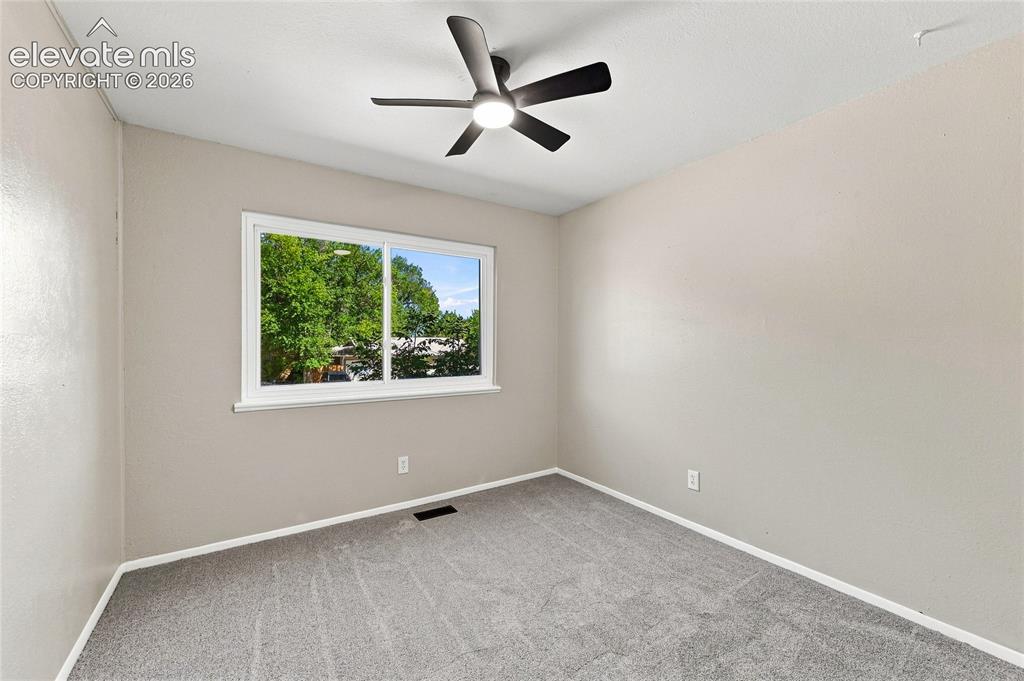 Image 18 of 30: Neutral-toned walls, carpeted flooring, and a modern ceiling fan with integ