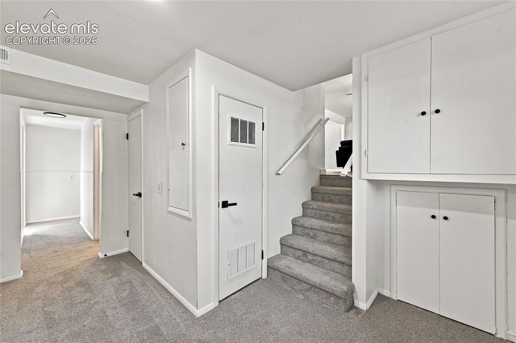 Image 20 of 30: Carpeted flooring extending into a hallway, white walls, and built-in stora