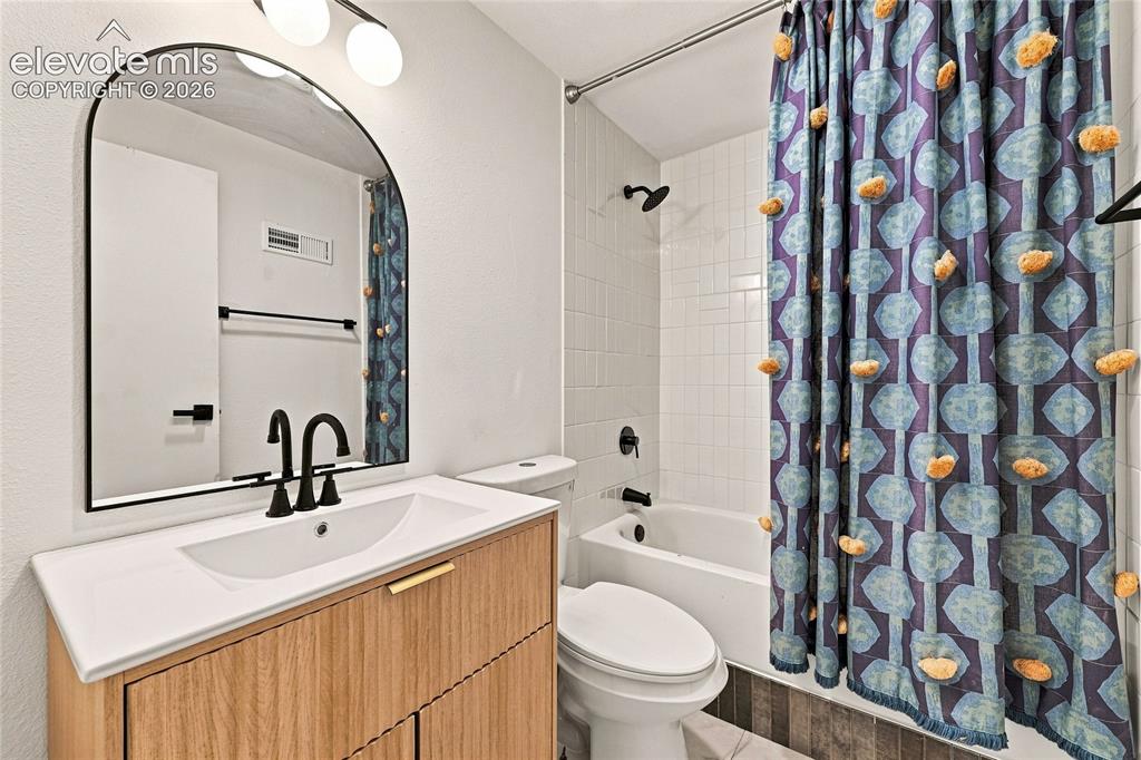 Image 23 of 30: Bathroom featuring a wood-finish vanity with an integrated sink, black hard