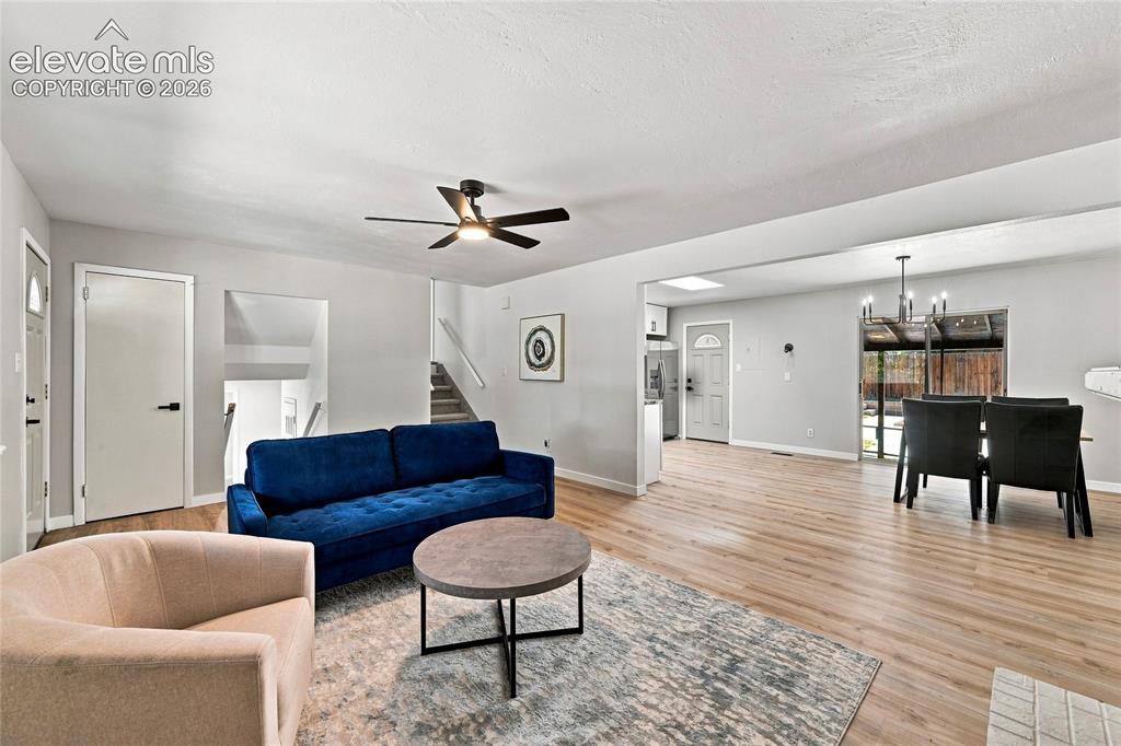 Image 4 of 30: Open-concept living area with wood-finish flooring, a ceiling fan with inte