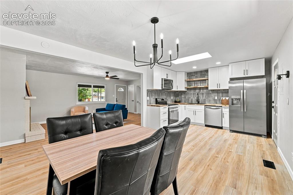 Image 7 of 30: Updated kitchen with white cabinetry and stainless steel appliances