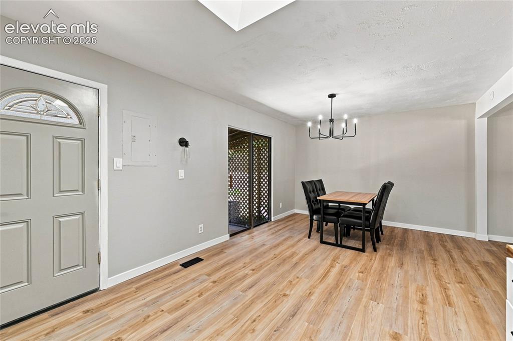 Image 8 of 30: Wood-finish flooring throughout, featuring a contemporary chandelier, a fro
