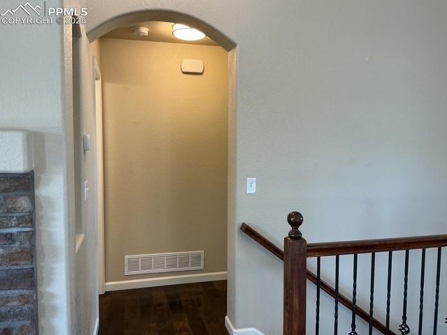 Image 13 of 37: Corridor featuring dark wood-type flooring, arched walkways, and an upstair
