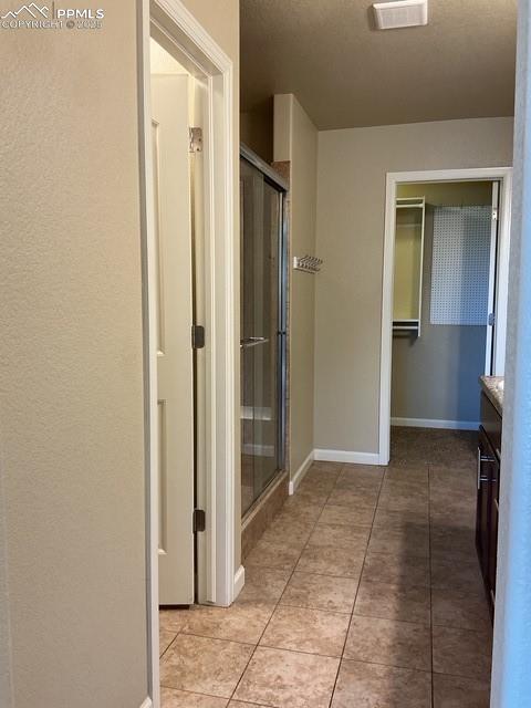 Image 21 of 37: Bathroom featuring a stall shower, vanity, a spacious closet, and light til