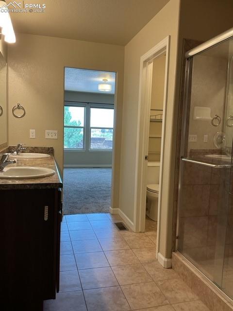 Image 22 of 37: Full bathroom with a stall shower, light tile patterned floors, double vani
