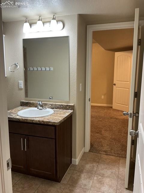 Image 31 of 37: Bathroom featuring vanity, a textured wall, light tile patterned flooring, 