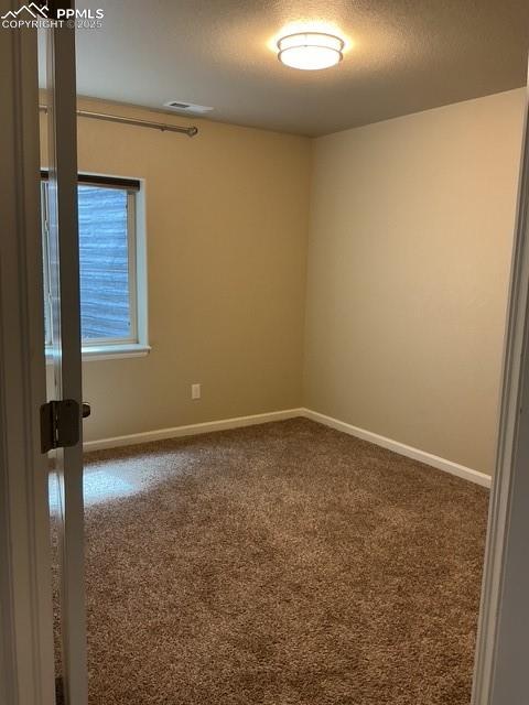 Image 34 of 37: 3rd Bdrm - Spare room with dark carpet and a textured ceiling