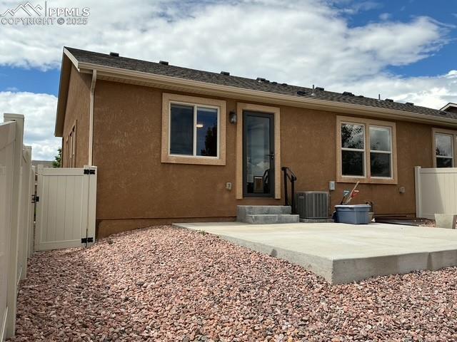 Image 5 of 37: Back of property featuring stucco siding, a gate, a patio area, and roof wi