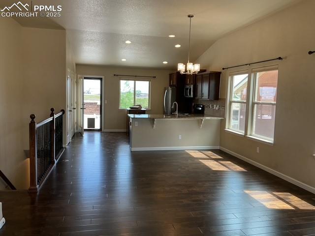 Image 8 of 37: Kitchen featuring a chandelier, a kitchen bar, dark brown cabinetry, plenty