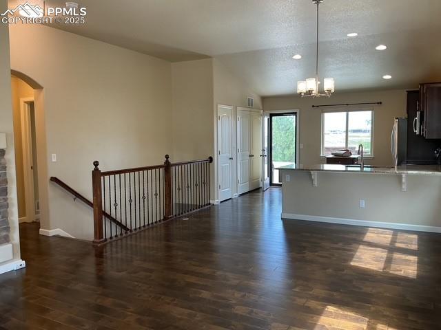 Image 9 of 37: Kitchen with a kitchen bar, light stone countertops, hanging light fixtures