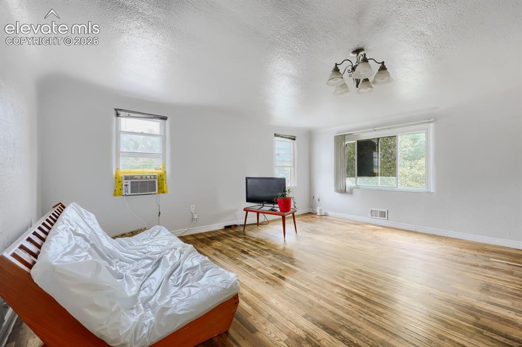 Image 13 of 36: Hardwood flooring throughout, multiple windows providing ambient light, and