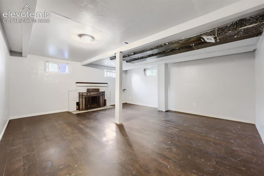 Image 16 of 36: Expansive room featuring wood-finish flooring, white painted walls, exposed