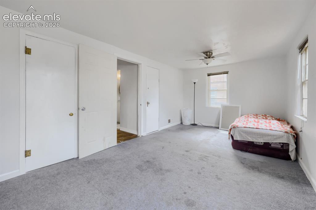 Image 20 of 36: Light grey carpet flooring, white painted walls, and a ceiling fan with lig