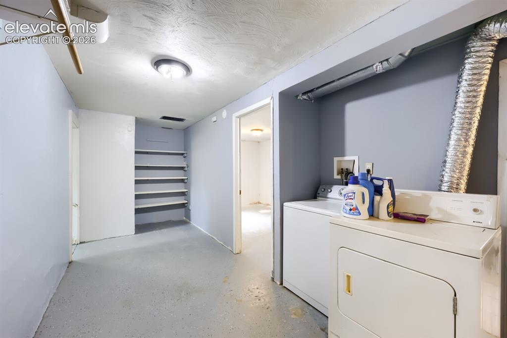Image 31 of 36: Dedicated laundry area featuring a washer and dryer, built-in shelving, and