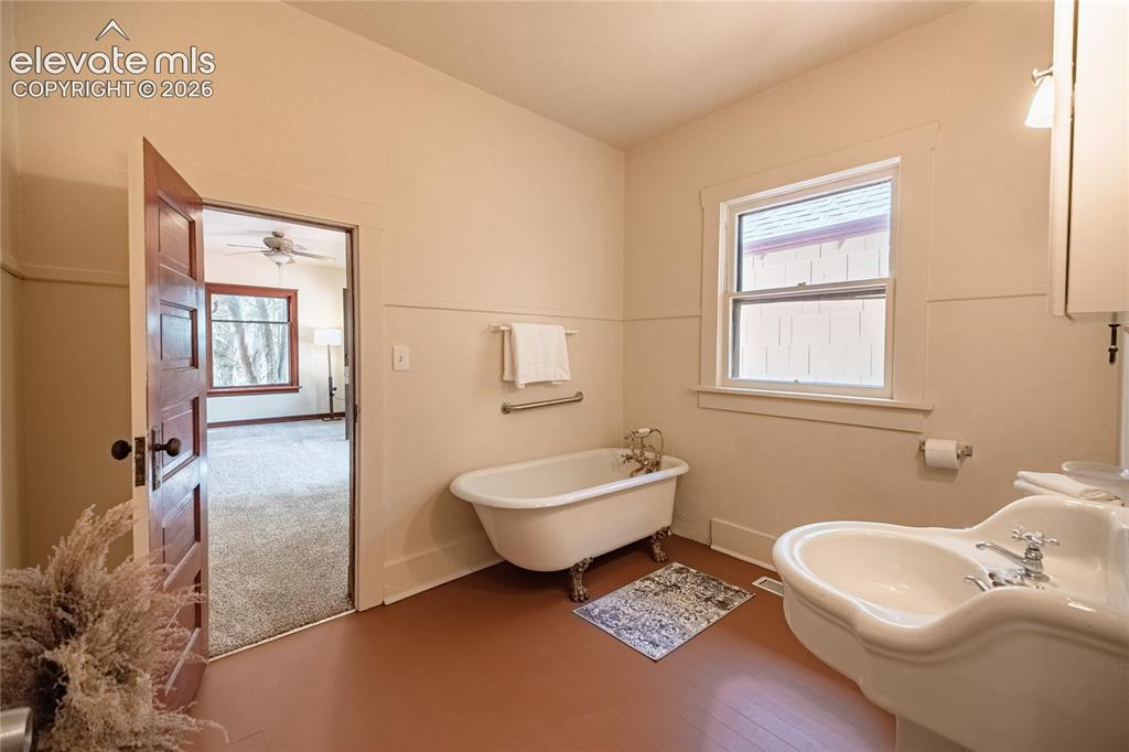 Image 15 of 47: Clawfoot bathtub with brass fixtures, pedestal sink with chrome faucets, wi