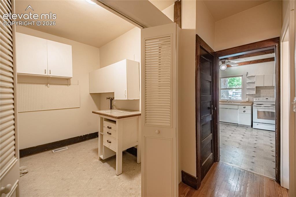 Image 16 of 47: Dedicated utility area featuring a built-in sink and upper cabinetry