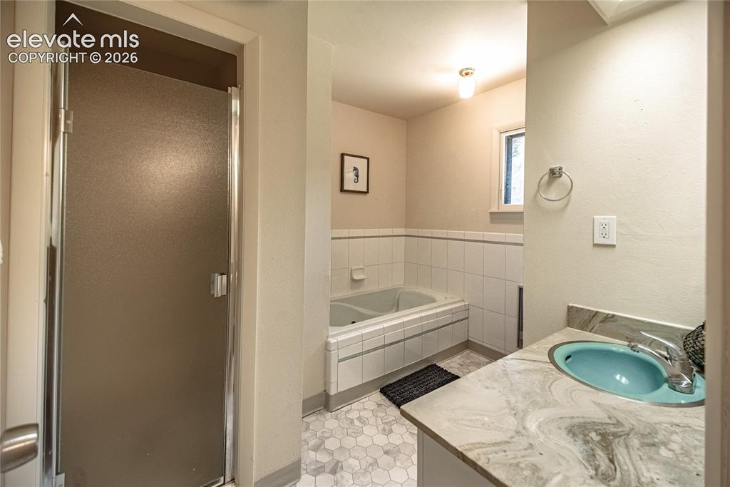 Image 22 of 47: Frosted glass shower enclosure, built-in bathtub, vanity with integrated si