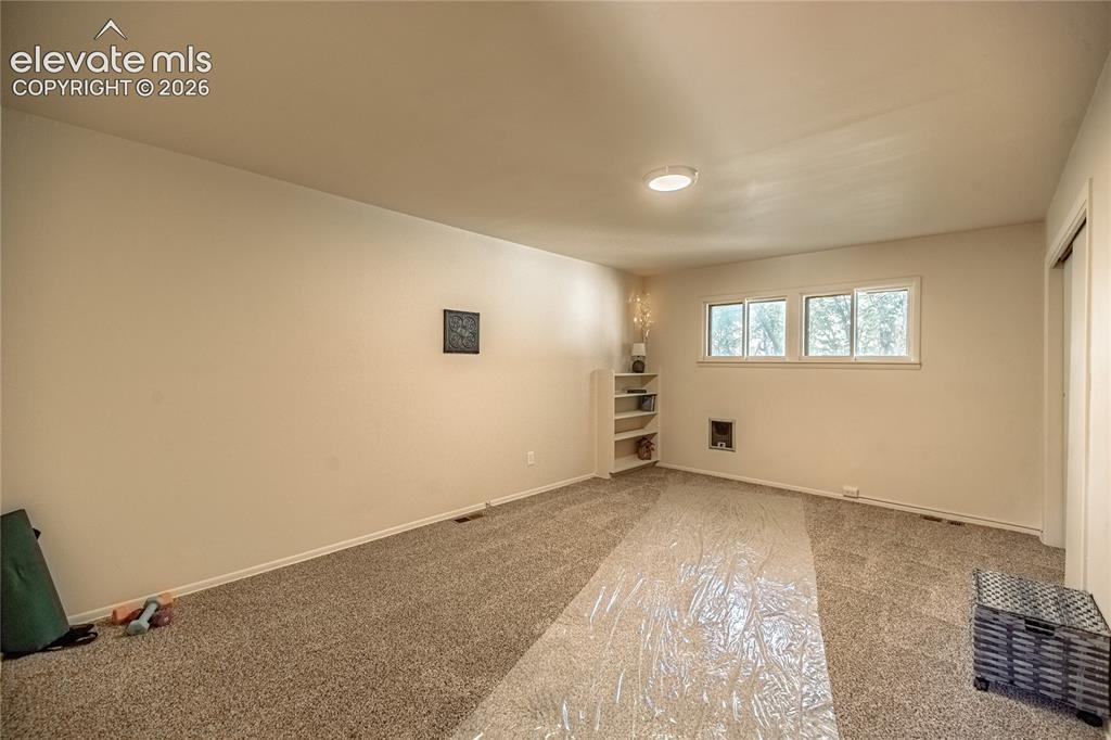 Image 23 of 47: Neutral wall paint, built-in shelving, and three windows with natural light