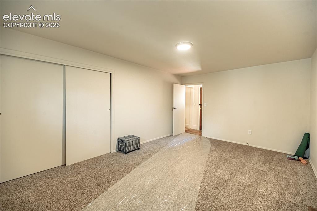 Image 25 of 47: Carpeted flooring, white interior walls, white sliding closet doors, and an