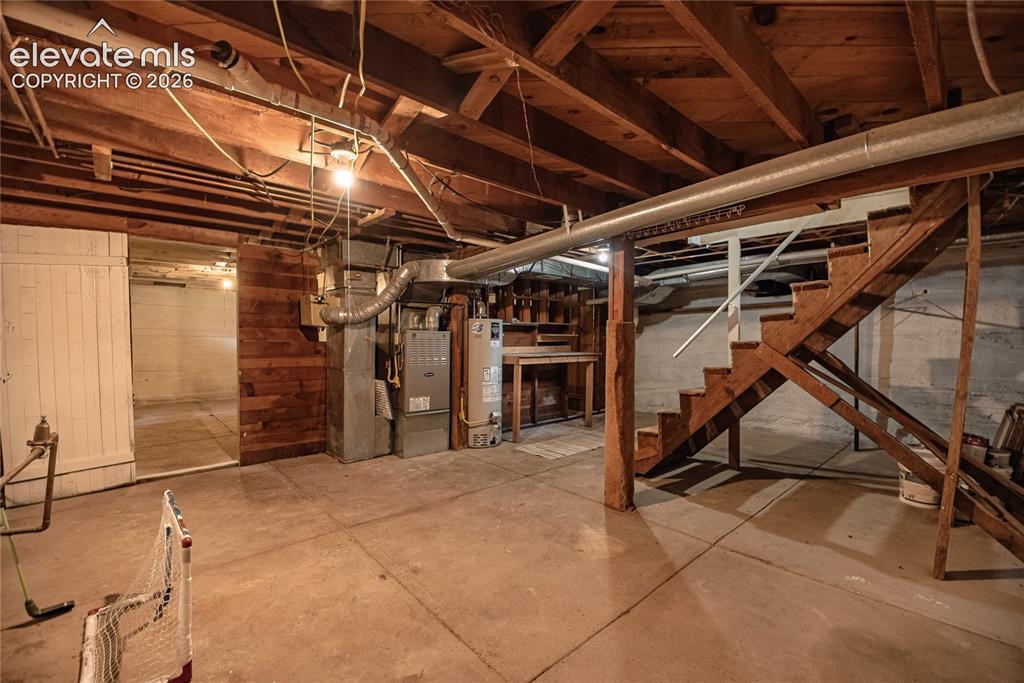 Image 27 of 47: Unfinished basement with concrete flooring and exposed wood ceiling joists