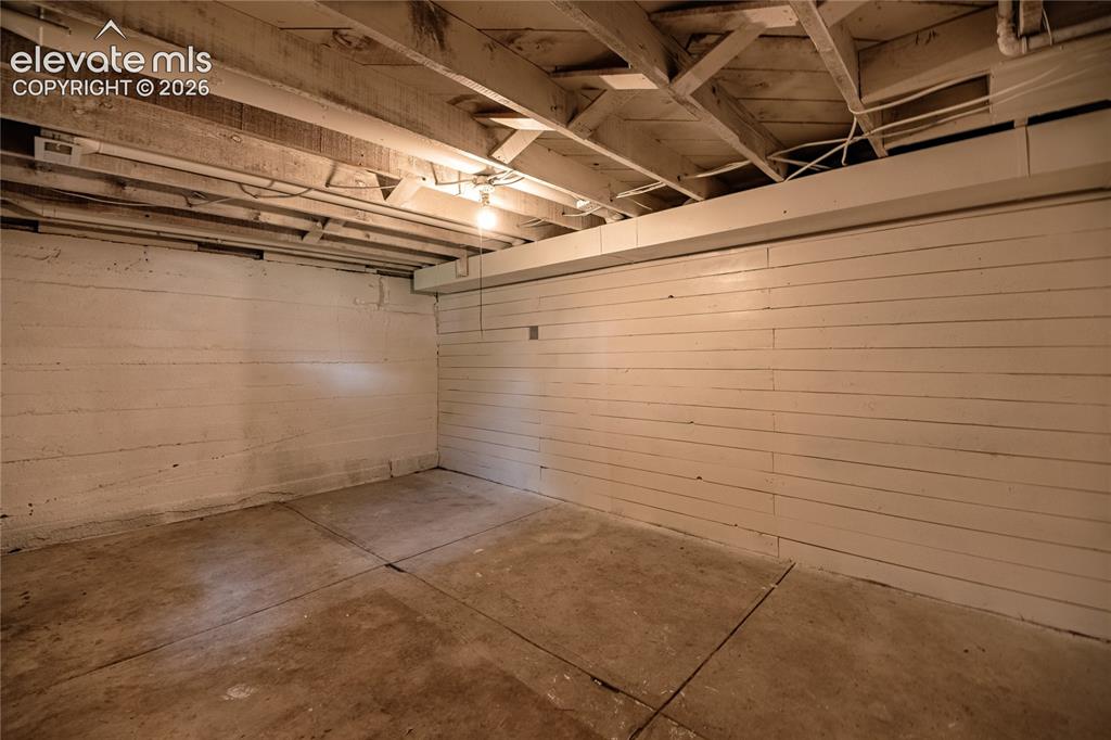Image 29 of 47: Exposed ceiling joists with visible electrical conduits, painted wood panel