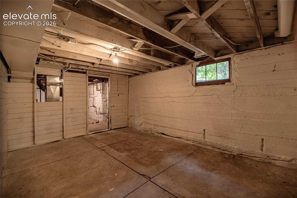 Image 30 of 47: Unfinished basement space with exposed ceiling joists, concrete flooring, a