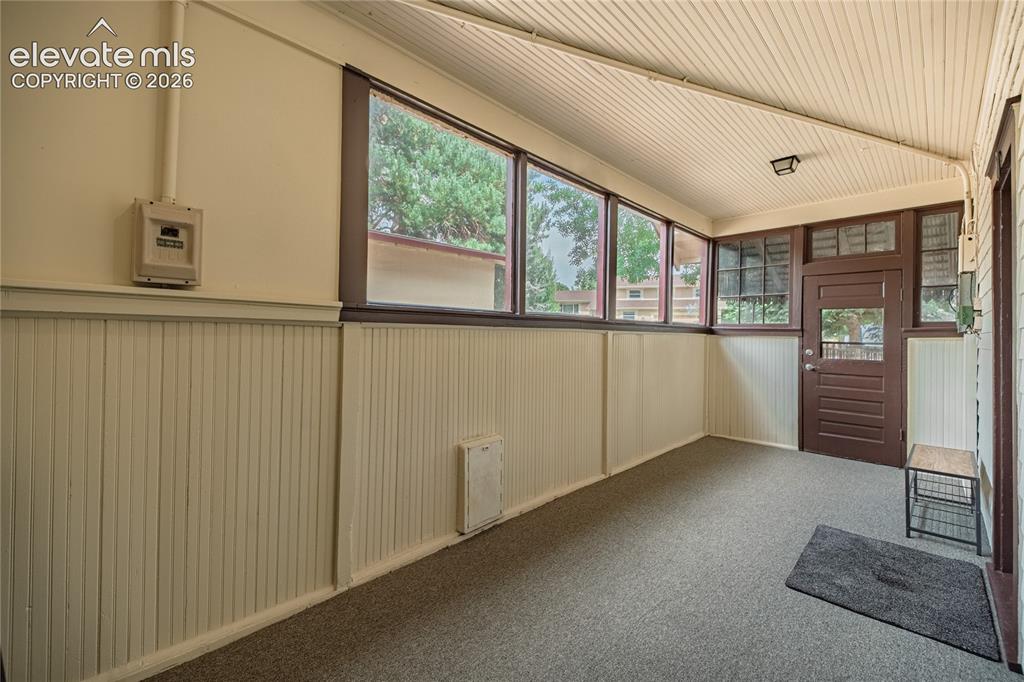 Image 31 of 47: Enclosed porch featuring multiple windows, paneled walls, and a wood-panel 