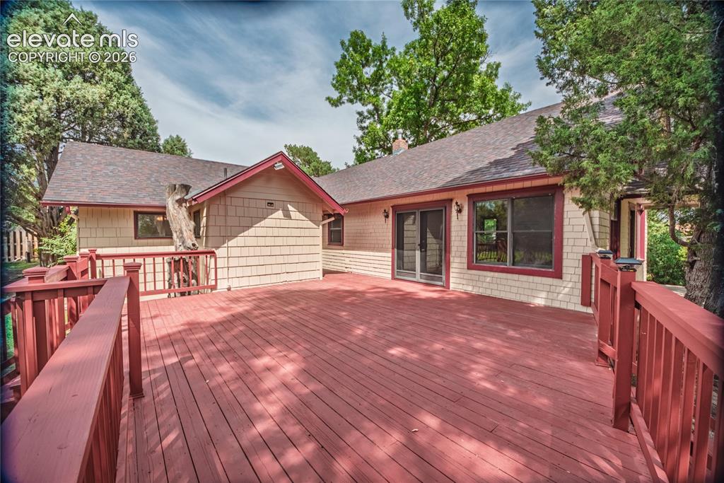 Image 32 of 47: Expansive outdoor deck with red-stained wood flooring and matching railings