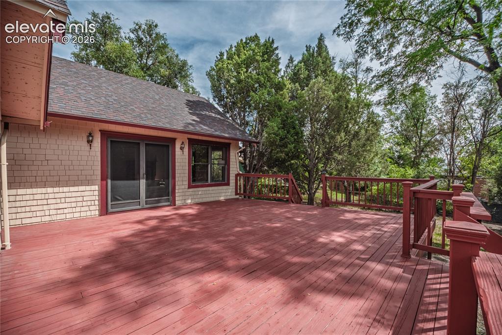 Image 33 of 47: Expansive wood deck with a red finish, featuring a matching wood railing an