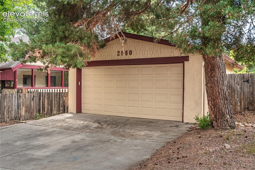 Image 35 of 47: Detached garage with Power and paneled door, stucco exterior, and accent tr