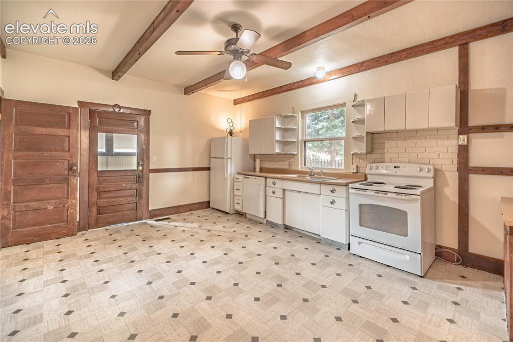 Image 4 of 47: Exposed wood ceiling beams, white cabinetry, wood-finish countertops, geome