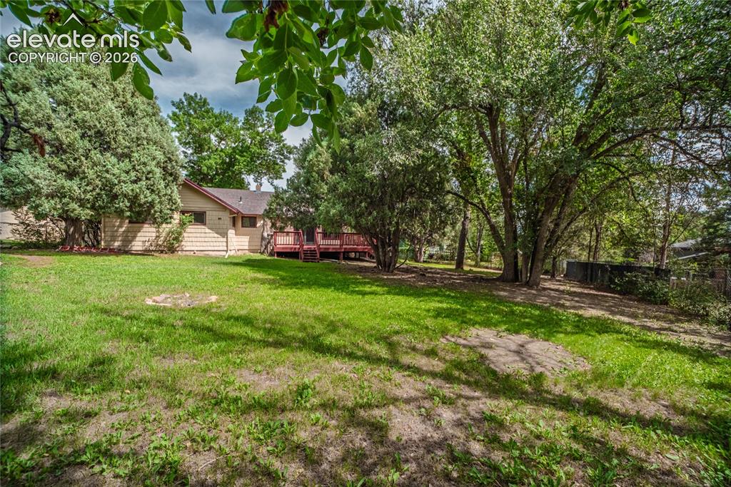 Image 40 of 47: Expansive backyard with a manicured lawn, mature trees, and a multi-level w