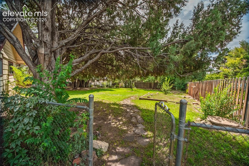 Image 44 of 47: Expansive yard space featuring a chain-link fence and gate, a stone pathway