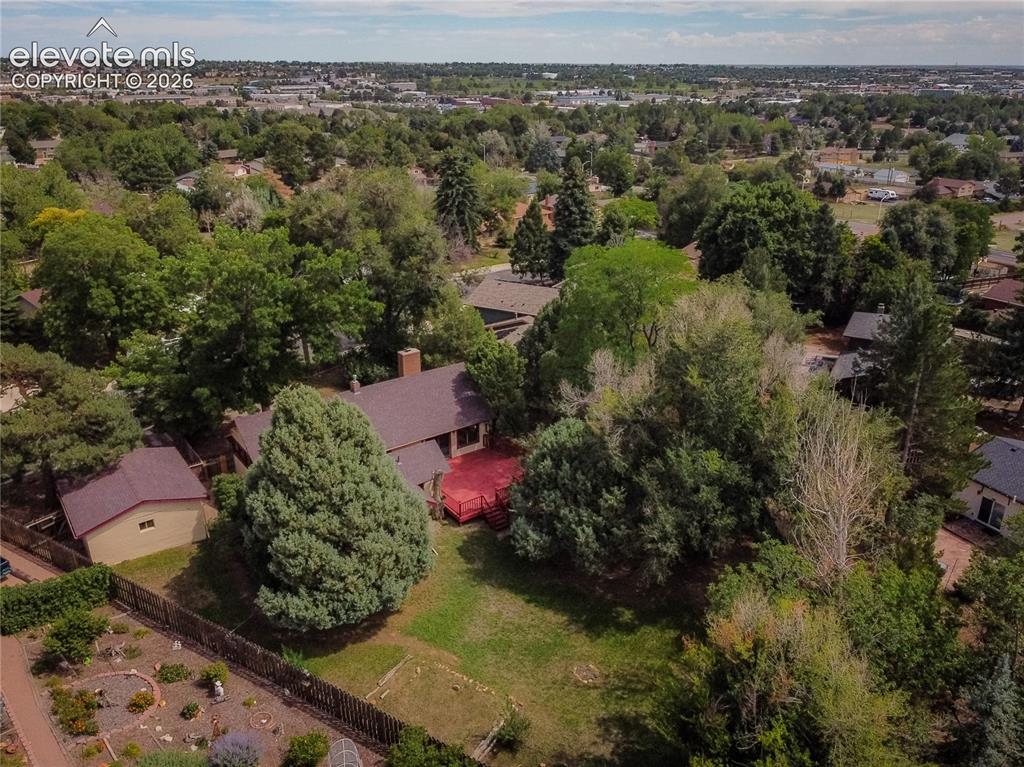 Image 45 of 47: Expansive property featuring lush mature trees, a red deck, a detached shed