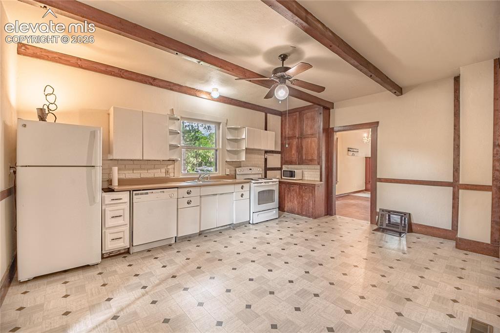 Image 5 of 47: Kitchen featuring exposed wood ceiling beams, a ceiling fan, white cabinetr