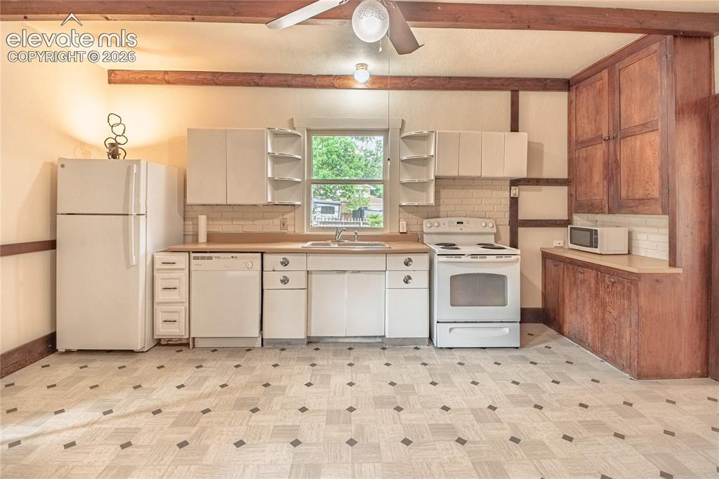 Image 6 of 47: Kitchen featuring white cabinetry, wood-finish countertops, tile backsplash