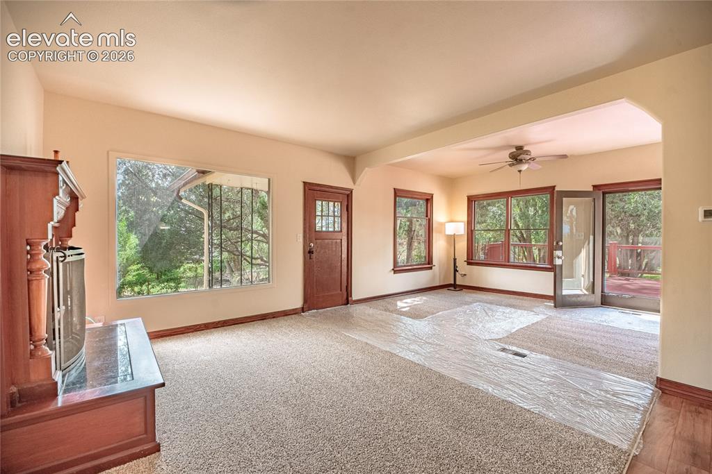 Image 9 of 47: Arched entryway, rich wood-frame windows, ceiling fan, wood-finish flooring