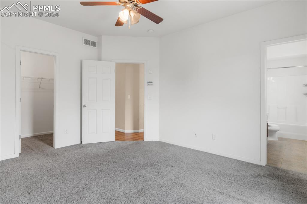 Image 10 of 30: Unfurnished bedroom with ensuite bath, ceiling fan, carpet floors, and a wa
