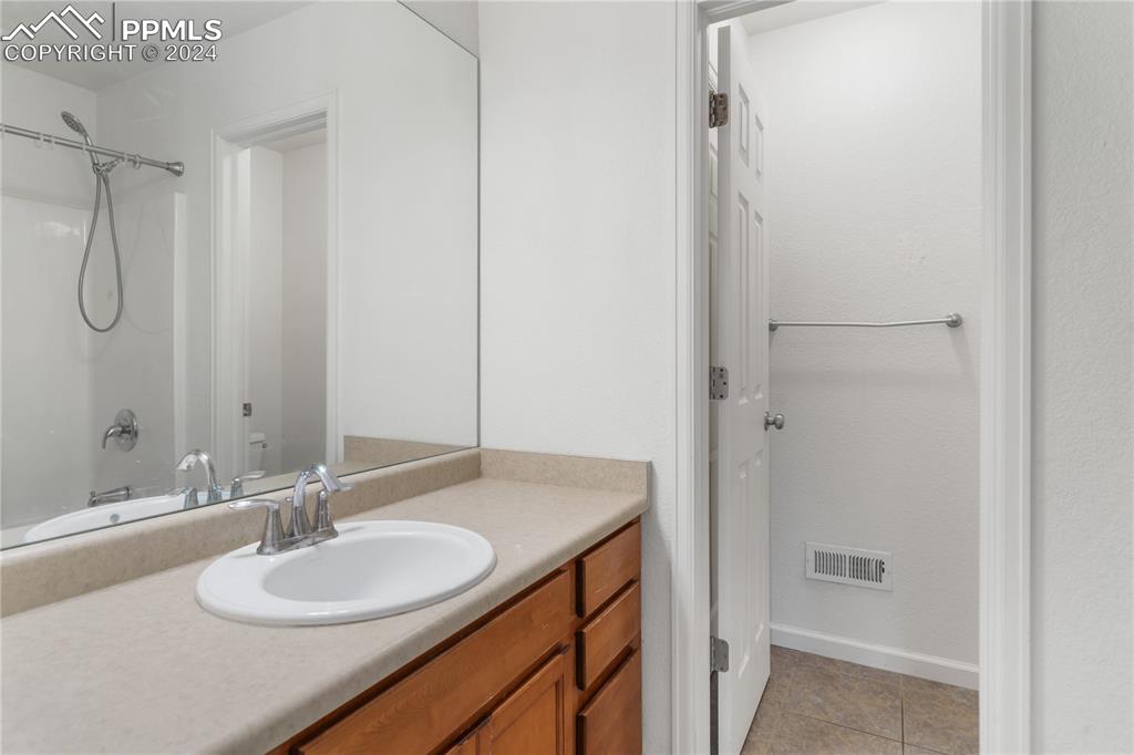 Image 13 of 30: Bathroom featuring tile floors, shower / bathing tub combination, and vanit