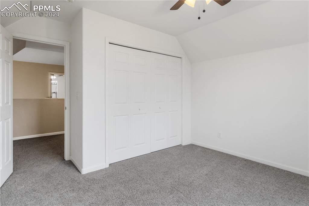 Image 19 of 30: Unfurnished bedroom featuring carpet flooring, a closet, lofted ceiling, an